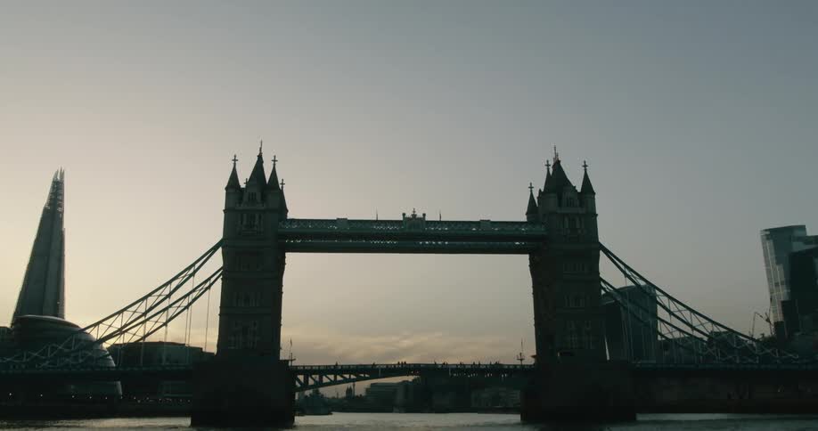People walking over London's Tower Bridge as the sun rises