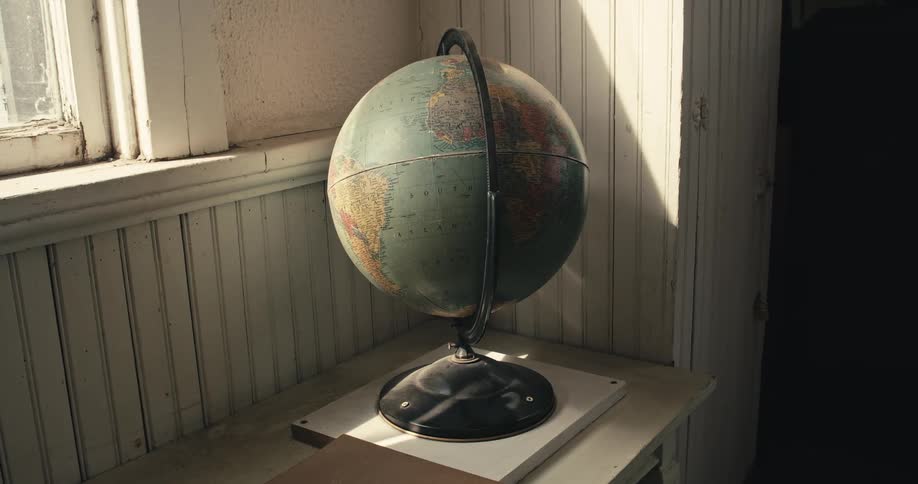 A globe sitting on a side table next to a window indoors