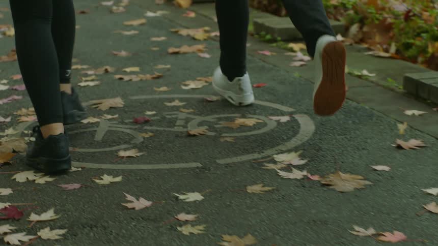 Friends jog through park along path during fall