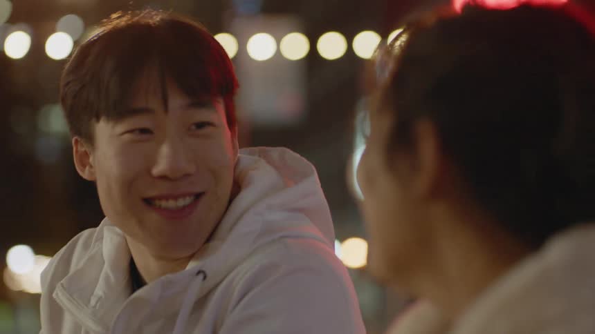 Two happy friends talking to each other in the city at night
