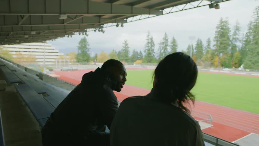 Friends talking to each other on the stadium bleachers at day
