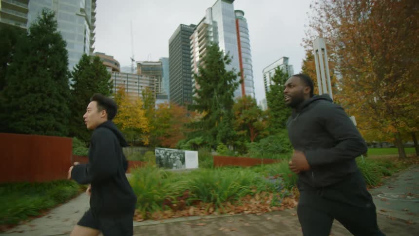 Two men jog together on the track by the city