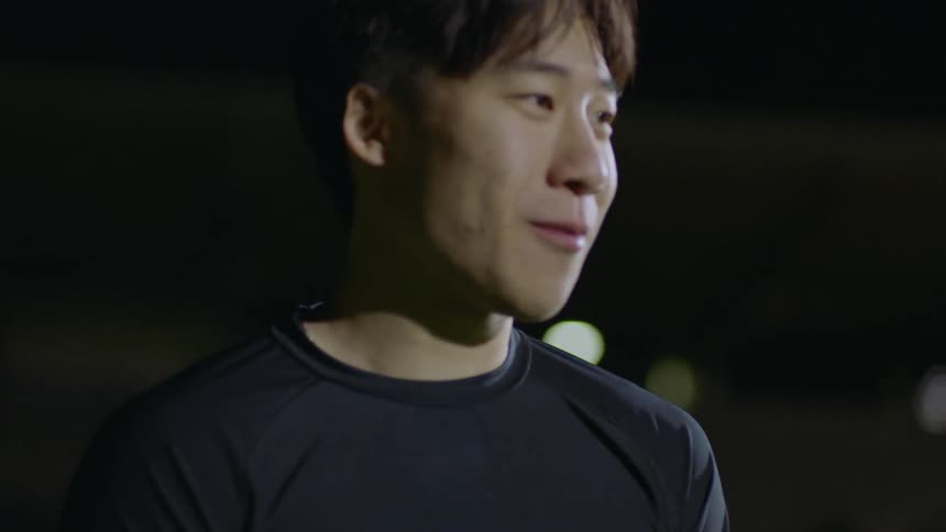 Two friends standing on a track field at night talk to each other
