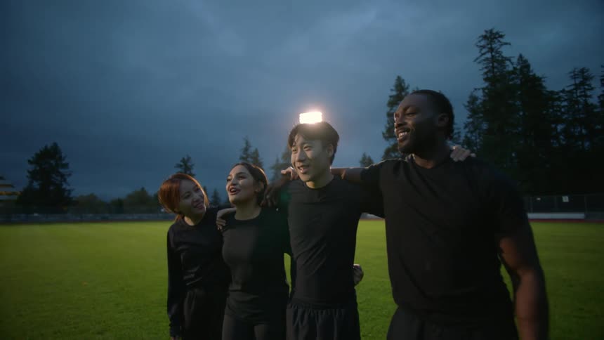 A group of friends talk and laugh on the field