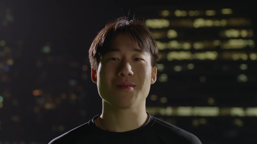 Young man wearing black clothes looks at the camera in front of a building at night