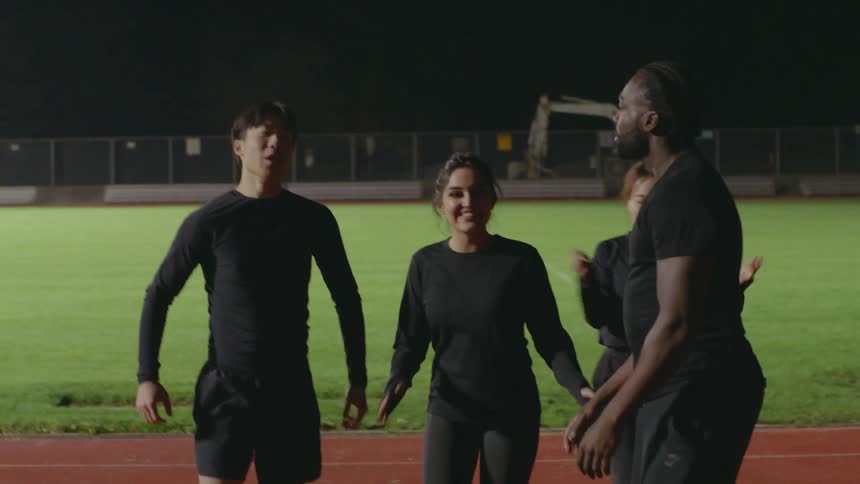 Two men and two women clap and cheer on a field