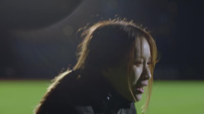 Young woman wearing black sports clothes working out with ropes on a field next to the city at night