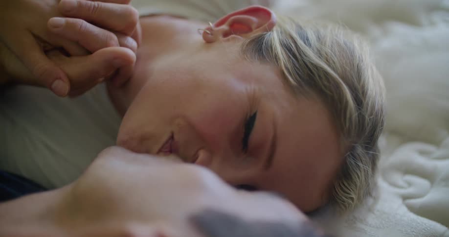 Young happy couple resting in bed kiss while holding hands