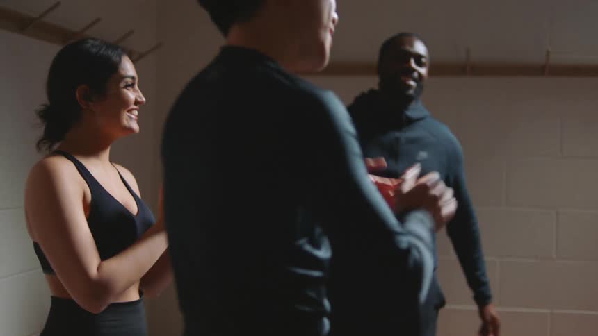 A young woman walks in to a room and her three friends clap and hive five her