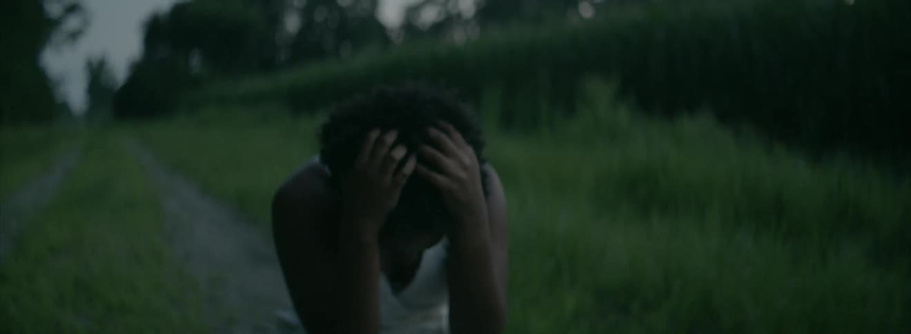 A woman knees on a path and runs her hands through her hair