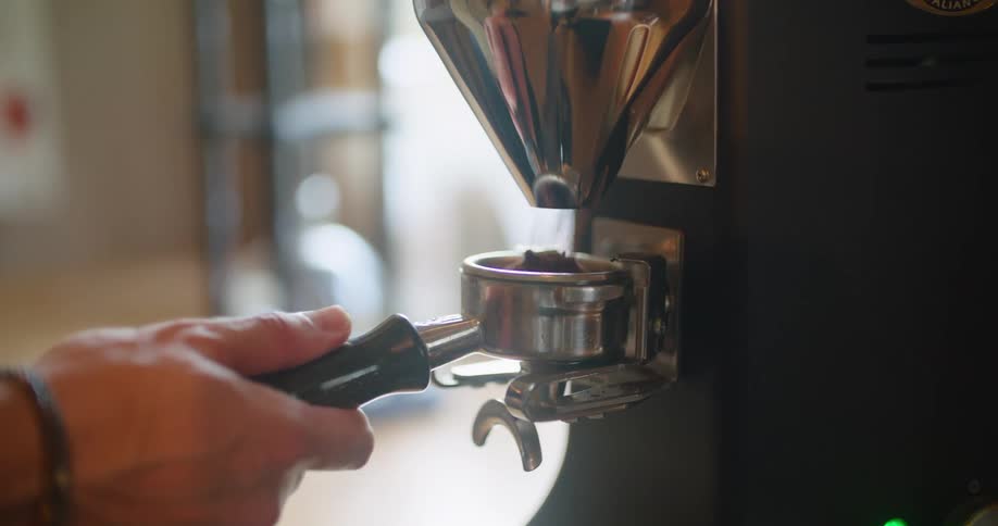Man pouring coffee on a espresso machine filter inside a store