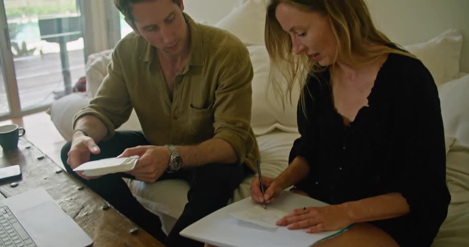 A man and woman writing and typing on a laptop together