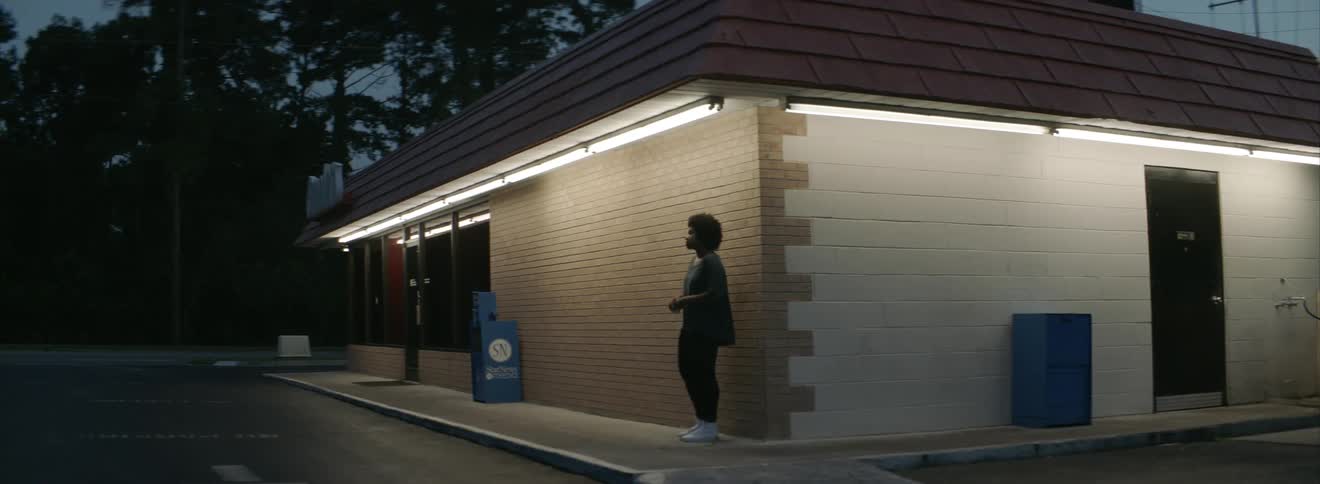 A woman stands near a building at sunset