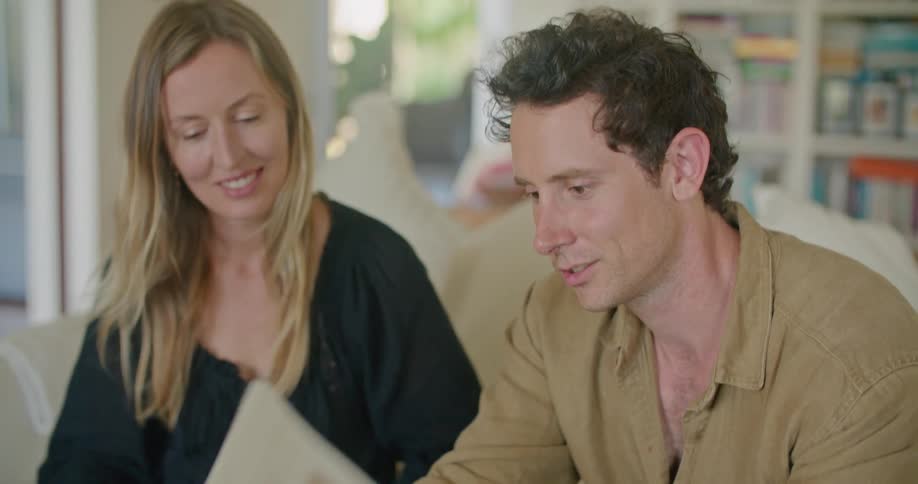 Man and woman sit on couch discussing flyers