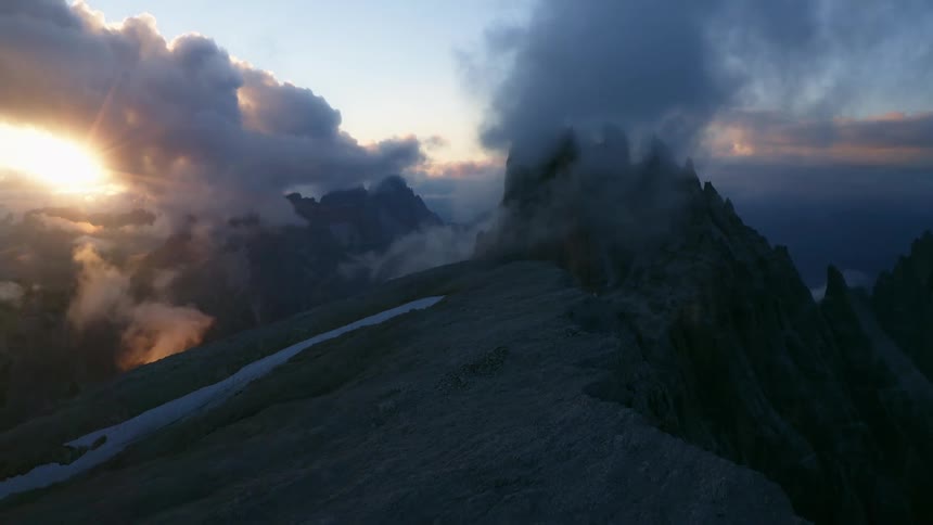 The clouds sit on the peak of the mountain at sunrise