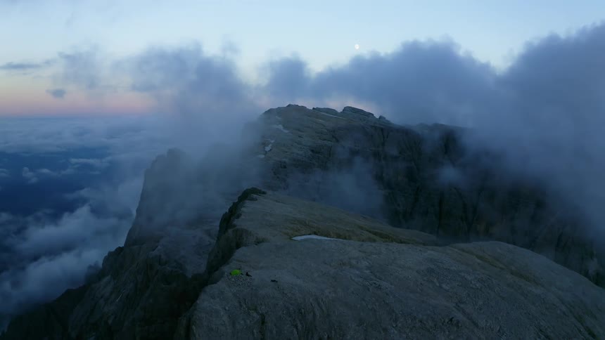Low lying clouds cover top of mountain with red tinted horizon in background