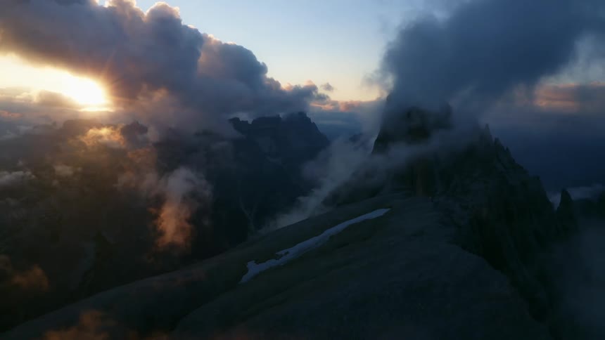 A mountain ridge shrouded in patches of mist at sunset
