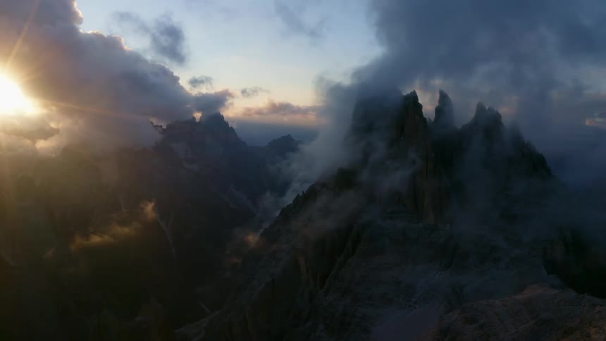Aerial view of high mountains surrounded by clouds as the sun shining brightly