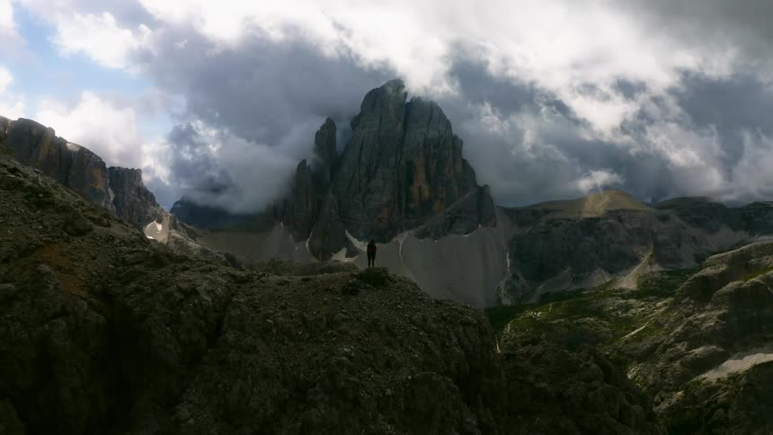 A person standing on a rocky ridge overlooking a mountain crater
