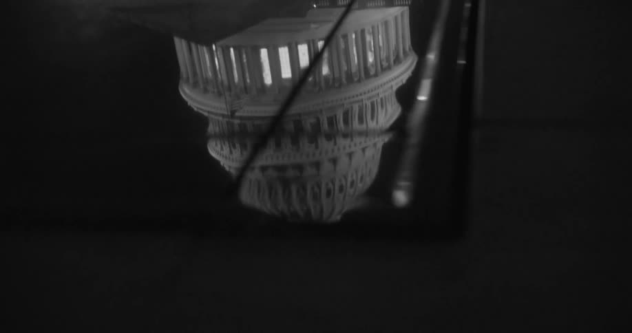 Reflective flooring shows white architectural building with several columns