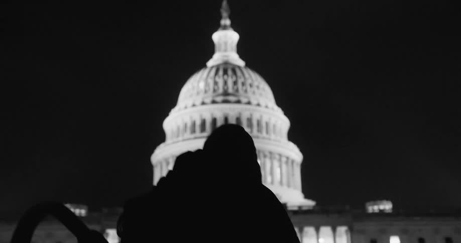 Person silhouetted against capitol building walks toward building at night