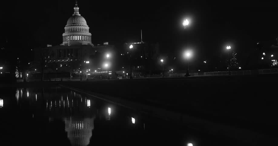Twisting footage of the us capitol reflecting on a pool at night
