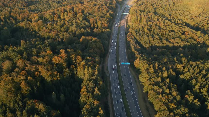 Aerial view of a busy highway and trees along the side of the road in fall colors