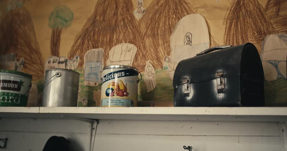 Cans and metal lunchboxes onve a small shelf on the wall