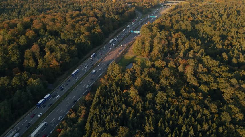 Aerial view of a busy highway and trees along the side of the road in fall colors