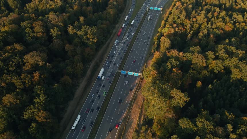 Traffic travels along a freeway through a forest during the day