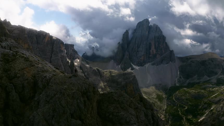 A hiker standing on a rocky mountain range in the wilderness on a cloudy day