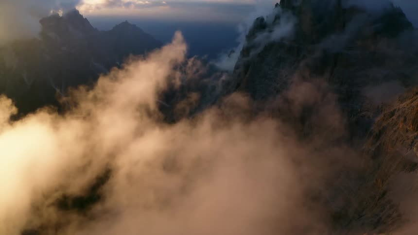 Clouds shroud a rock mountain ridge during the day