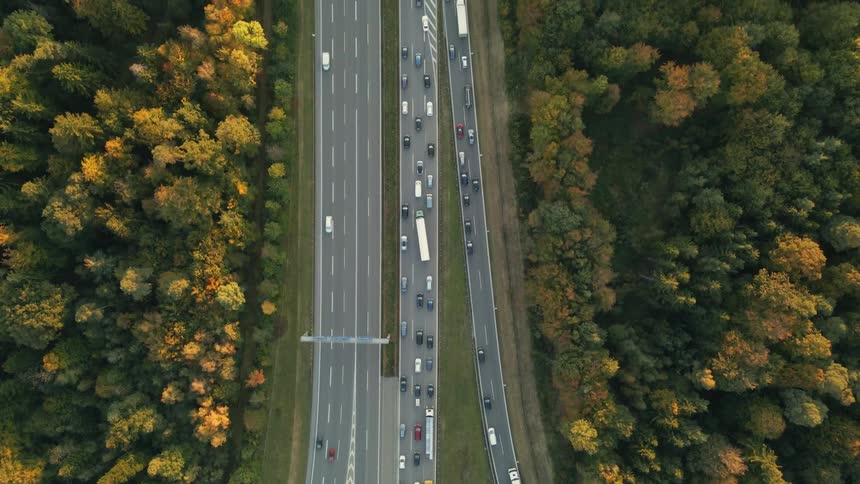 Aerial view of a busy highway and trees along the side of the road in fall colors