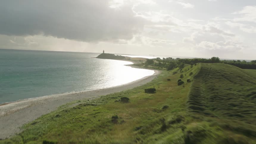 A beach along the coast of a land mass on a cloudy day