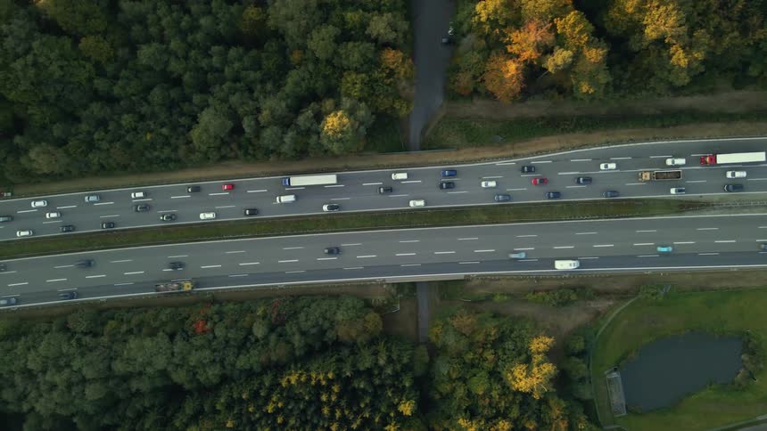 An aerial view of highway traffic flowing through a woodland area in the daytime