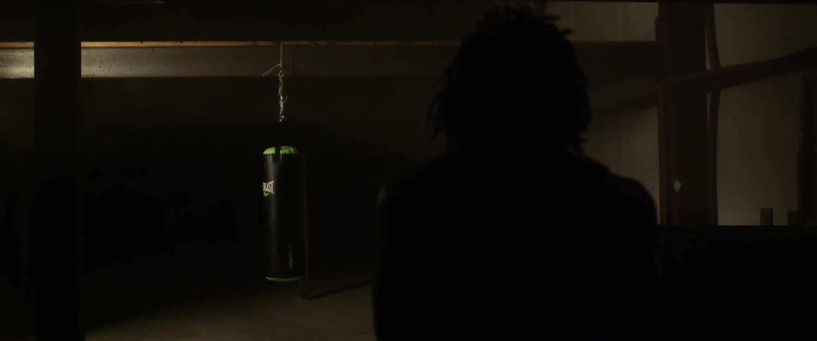 A person is walking in a very dark gym