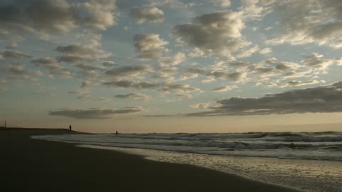 Waves roll into a beach at sunset