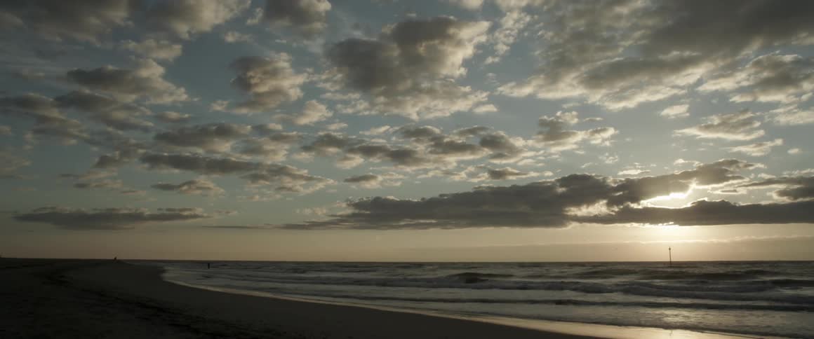 In the distance a person walks in the shallow water
