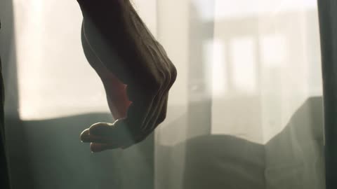 A person stands in front of a sheer curtain