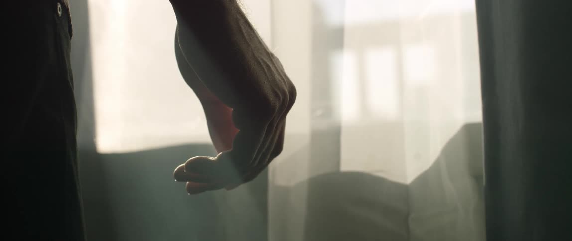 A person stands in front of a sheer curtain