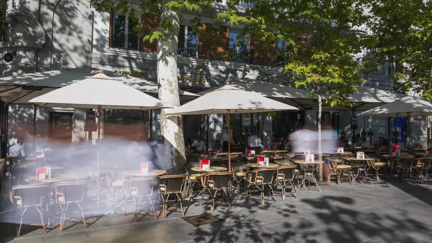 Pedestrians walk past the outdoor dining area of the restaurant