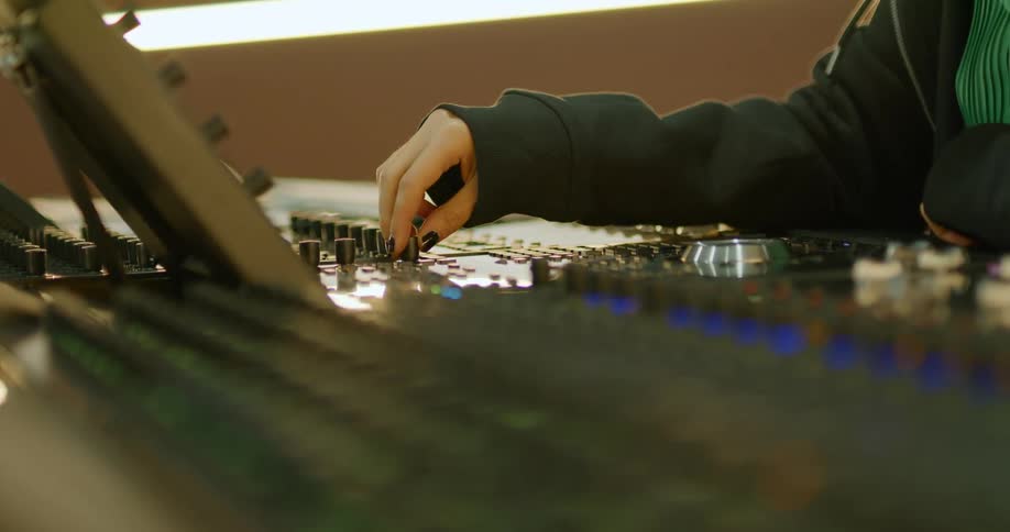 A person turns the knob on a soundboard