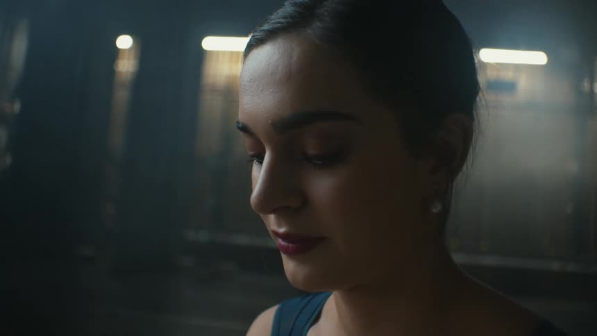 Young elegant woman standing inside a dimly lit room with flashing lights