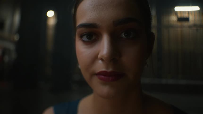 Woman wearing lipstick raises head to face forward