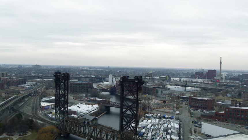 Aerial view of a bridge over a river in the industrial area of a city at evening