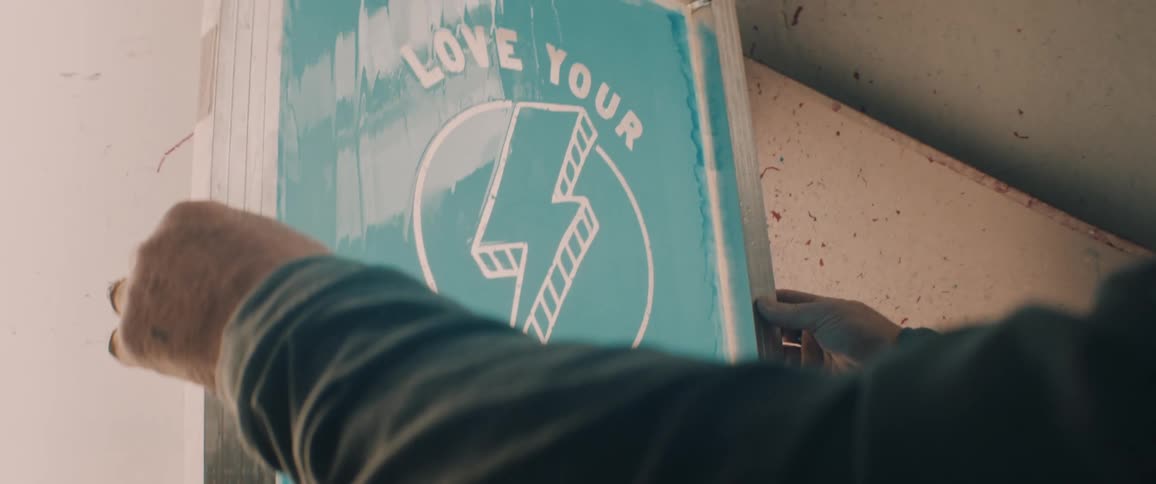 Man washing a screen to reveal a design for screen printing on his worhskop