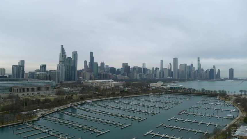 Aerial view of a marina in front of a waterfont city skyline at evening