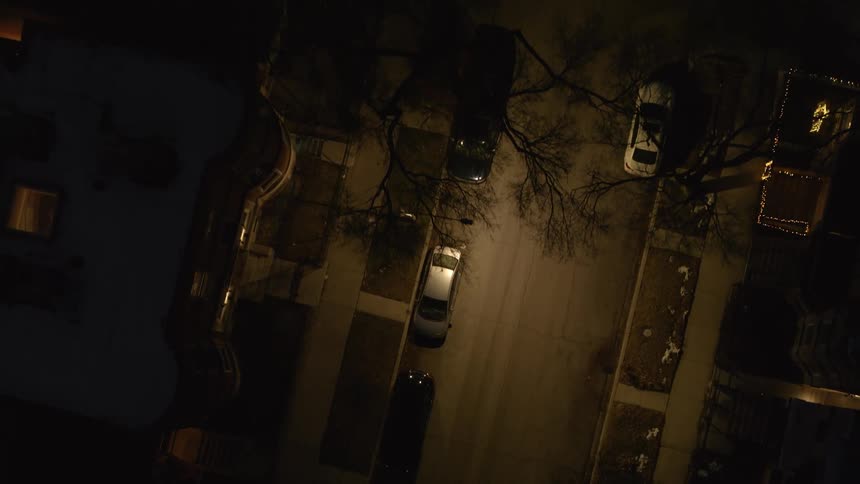 A car drives down the neighborhood street at night
