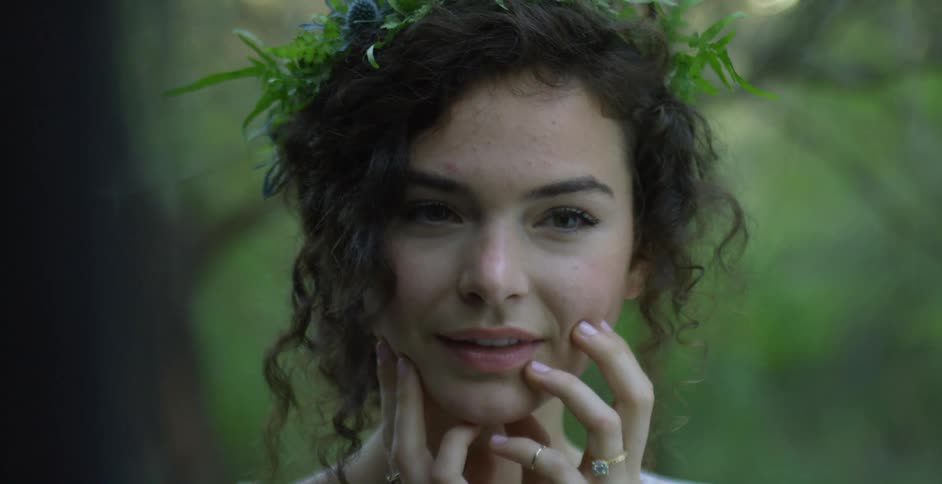 Woman wearing flower wreath poses while smiling