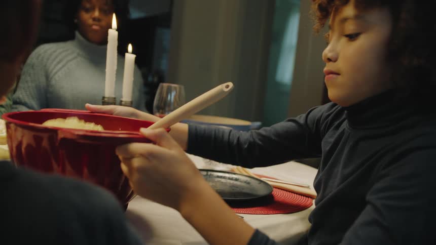 Mother watches daughter pass noodles to brother
